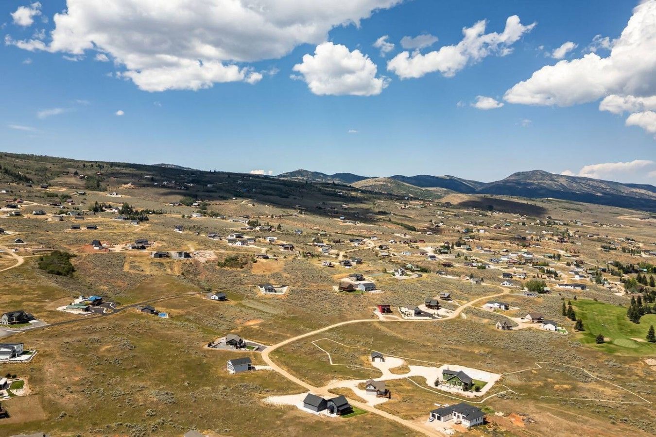 A rural landscape with scattered houses, roads, and a mountain range in the background.
