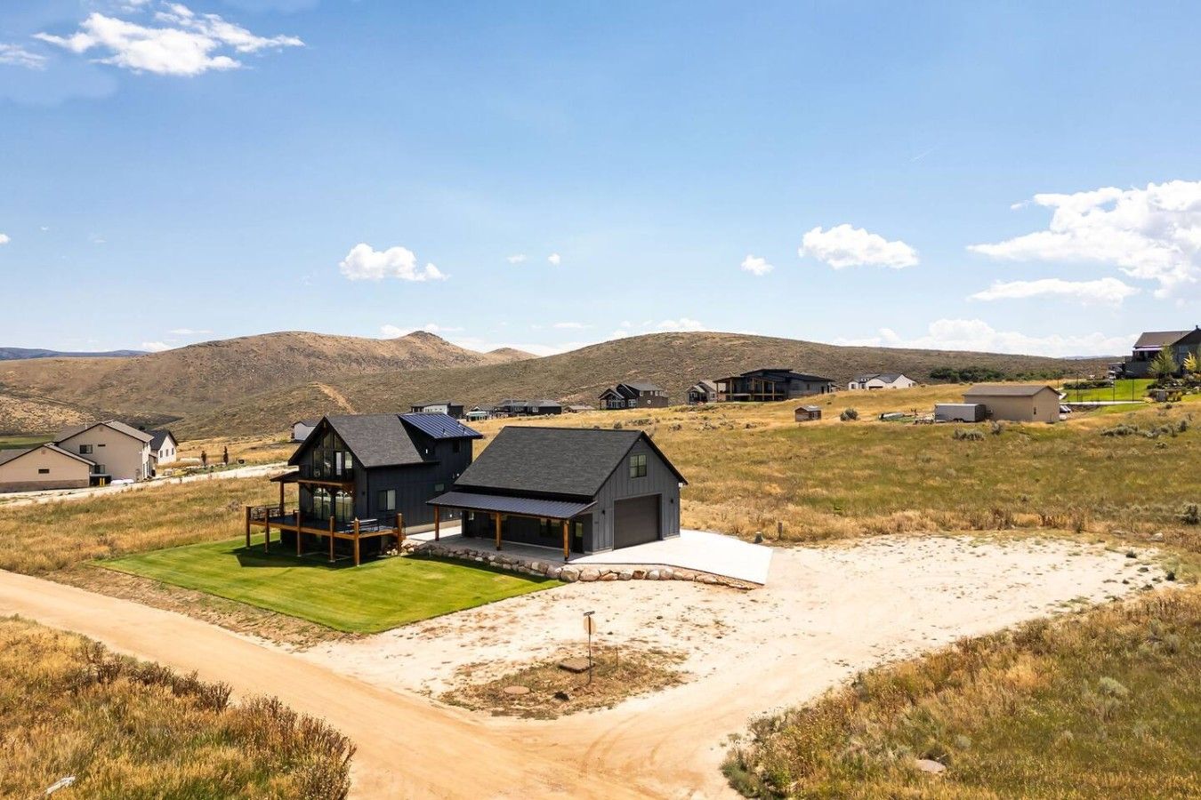 Una zona residencial con casas, un camino de tierra y un campo cubierto de hierba.