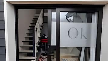 Un interior moderno con una escalera que lleva a una plataforma, una puerta de cristal con picaporte y una alfombra estampada en el suelo.
