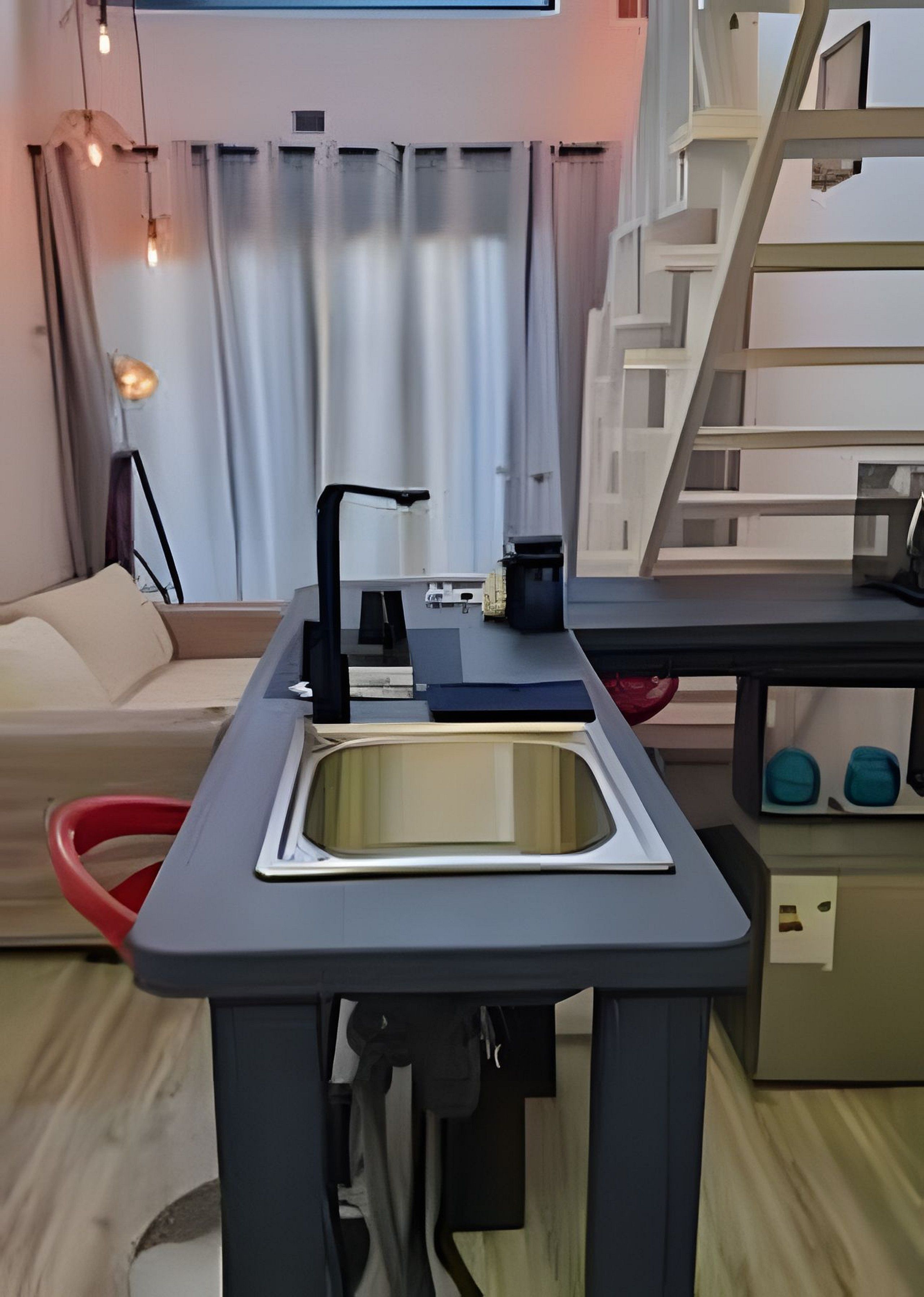 A compact kitchen with a sink, countertop, and a small table with a coffee maker.
