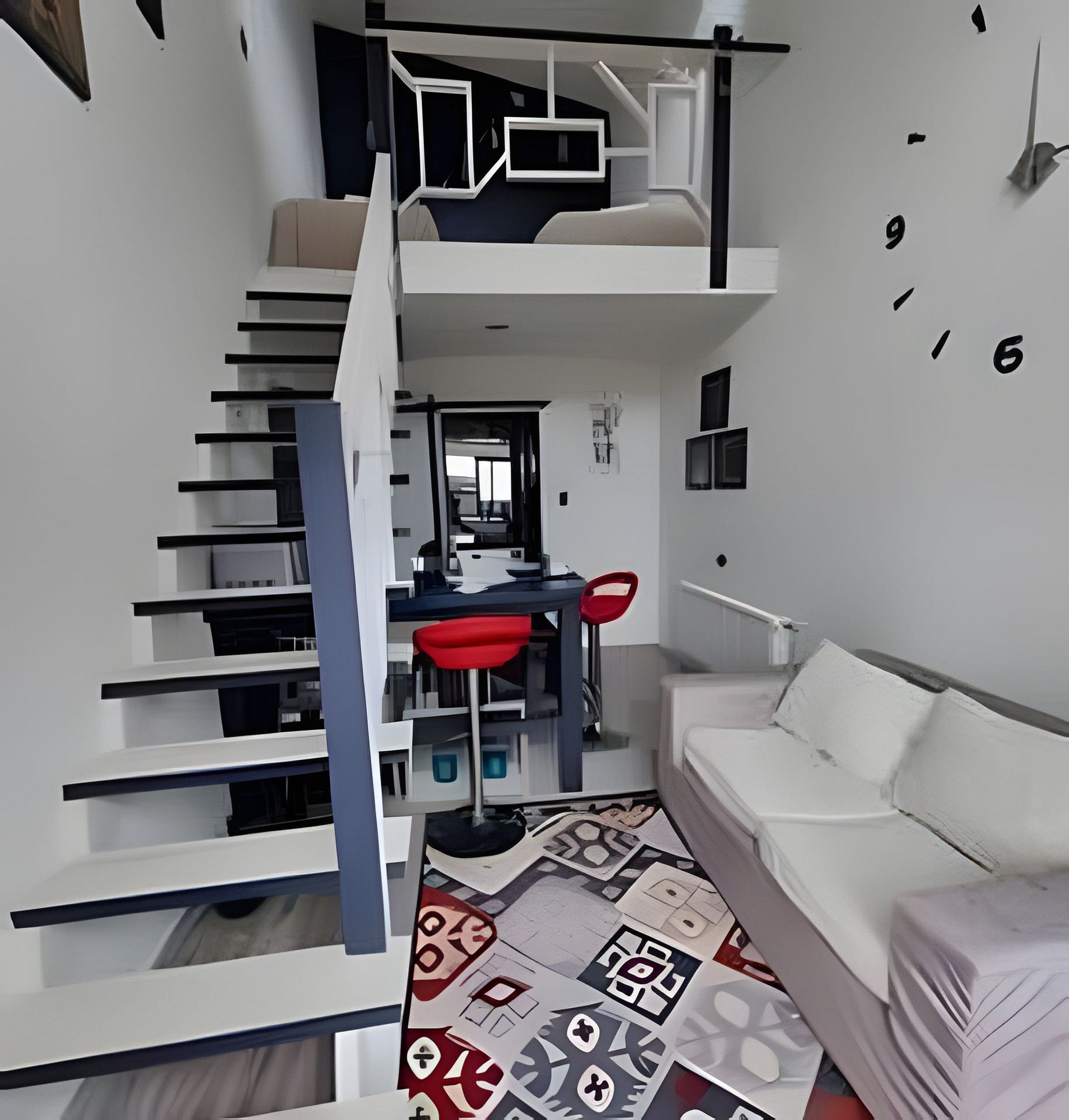 Un interior moderno con una escalera que lleva a una zona de altillo, una mesa de comedor con sillas y un sofá.