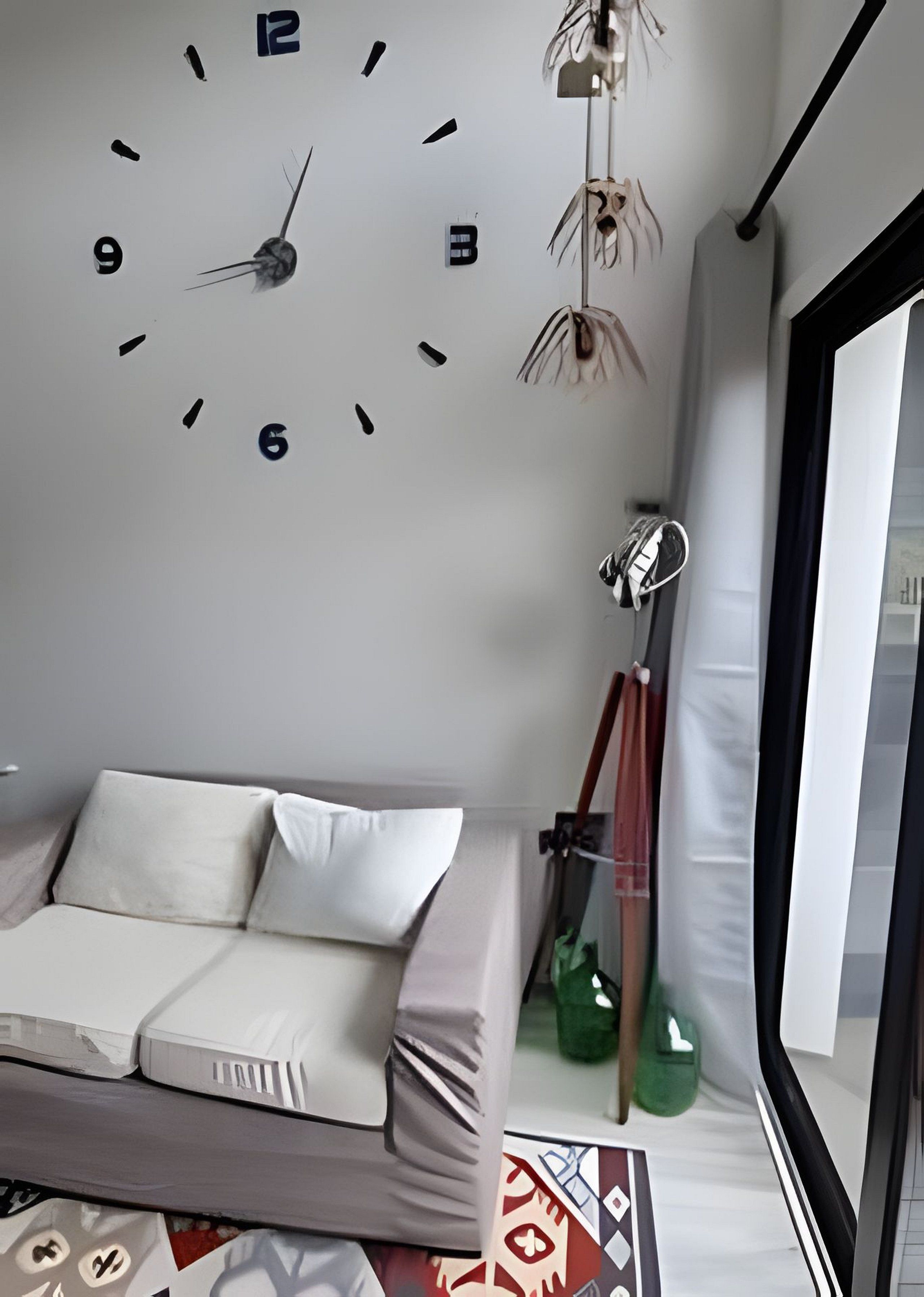 Ein modernes Wohnzimmer mit einer Couch, einer Wanduhr und einem großen Fenster.