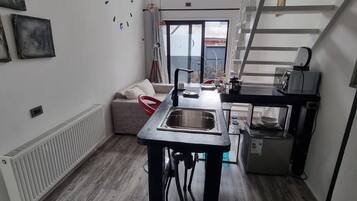 A modern kitchen with a central island, a built-in oven, and a window overlooking a balcony.
