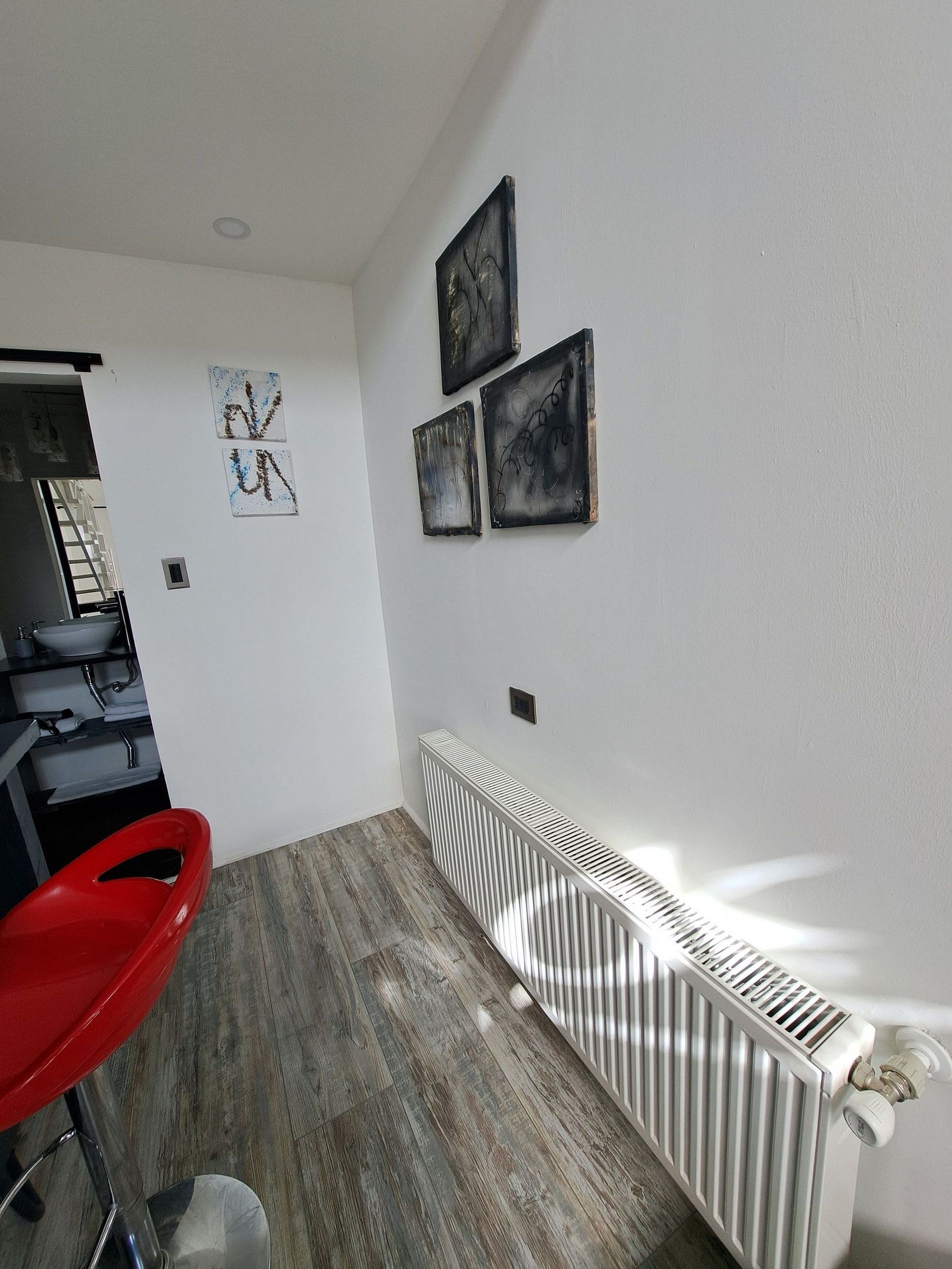 A modern kitchen with a built-in oven, a red chair, and a white radiator.
