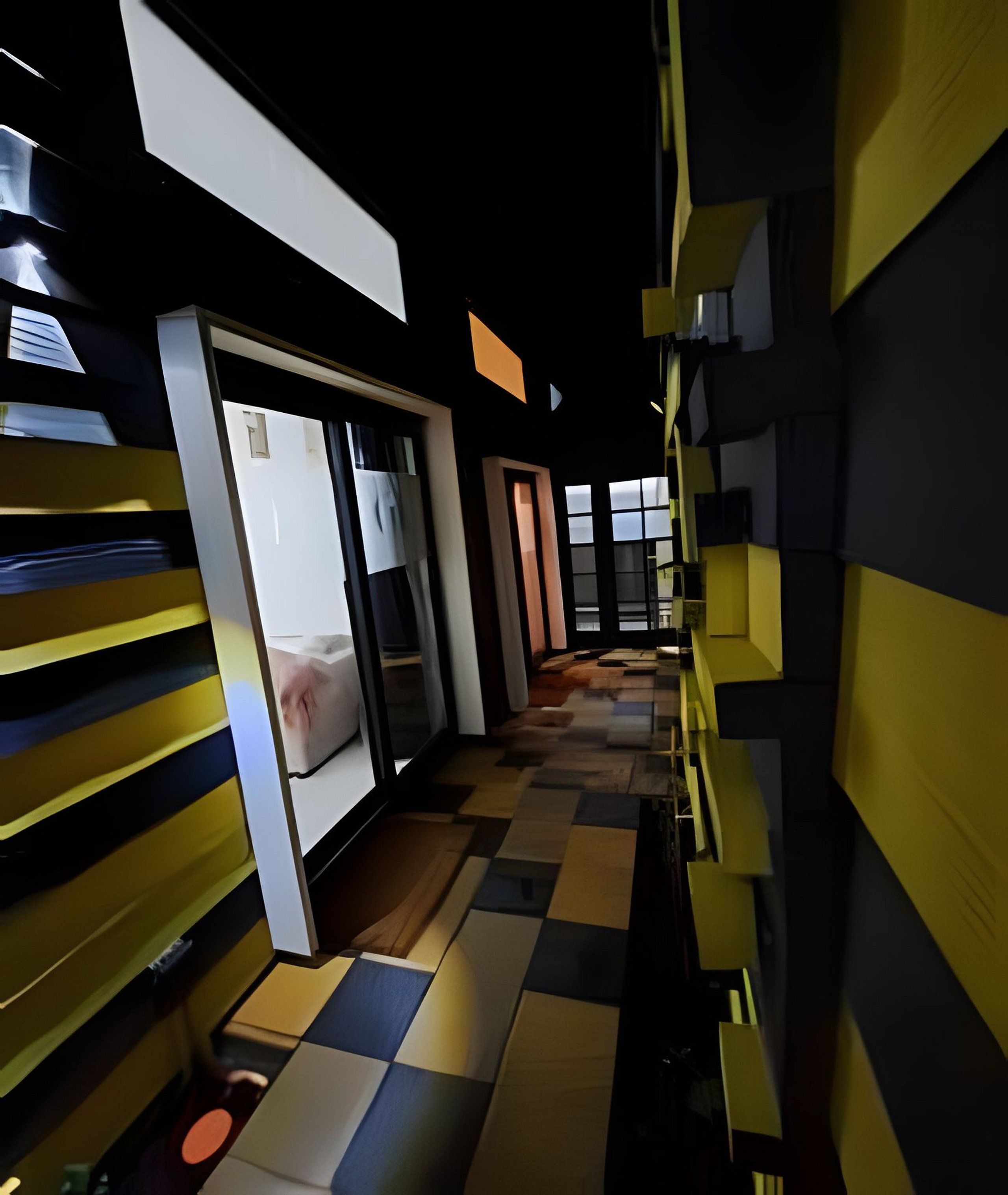 A hotel corridor with a checkered floor pattern, a sliding door, and a view into a room.