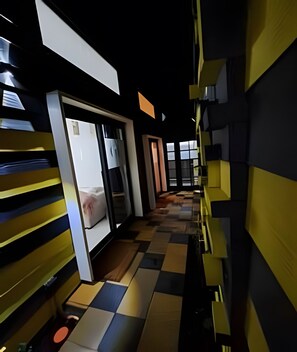 Un pasillo de hotel con un estampado de cuadros en el piso, una puerta corredera y vistas a una habitación.
