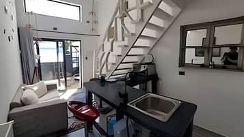 Un espacio habitable moderno con escalera, comedor y sofá.
