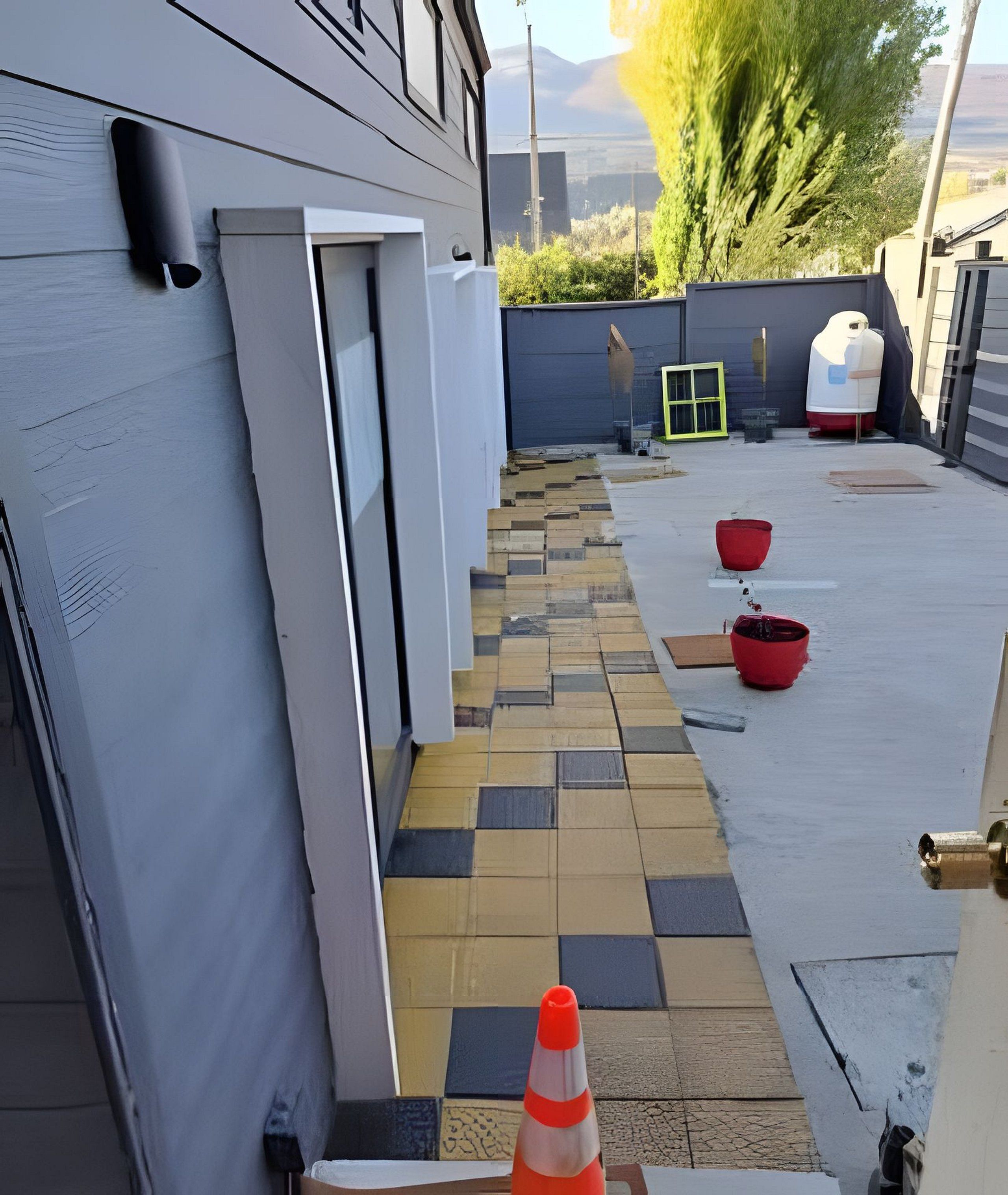 Un estrecho sendero exterior con un diseño de baldosas en damero que conduce a la entrada de un edificio.