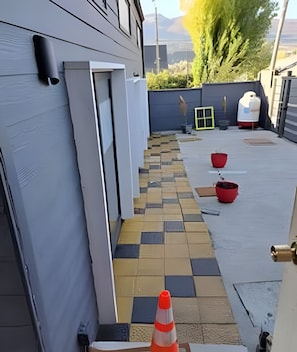 A narrow outdoor pathway with a checkered tile pattern leading to a building entrance.