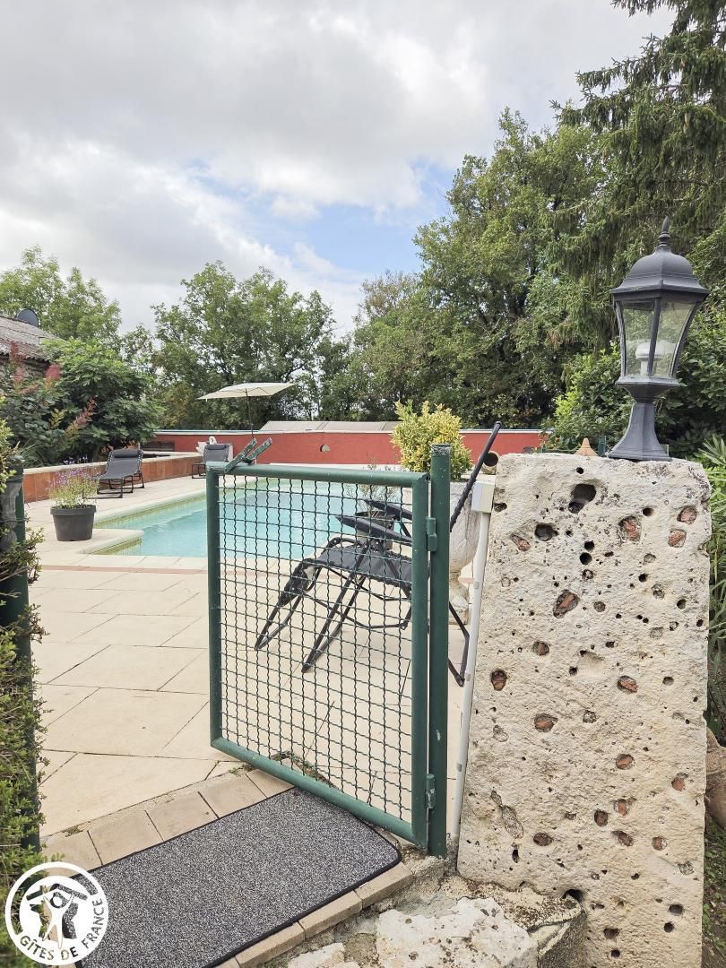 A gated outdoor area with a pool, a wheelchair, and a stone wall.