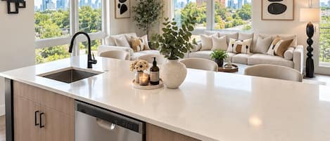 Una cocina moderna con una isla central, lavavajillas integrado e iluminación colgante.