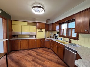 Eine Küche mit Holzausstattung, einem Einbauofen, einem Spülbecken und einem Fenster mit Jalousien.