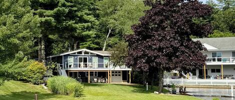A lakeside property with a house, dock, and docked boat.