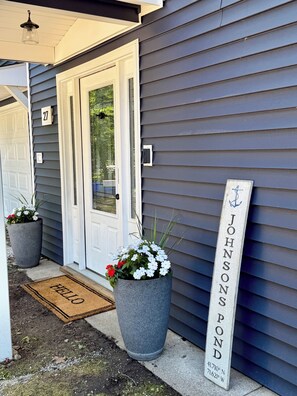A house entrance with a mailbox, a welcome mat, and a nameplate.
