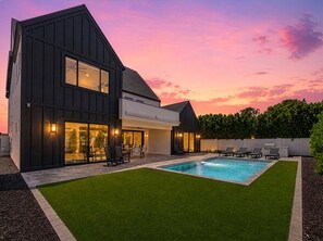 A modern two-story house with a swimming pool, a patio with outdoor furniture, and a well-maintained lawn. - Valencia - 35' Ceilings - Private Pool - Biltmore (Phoenix)