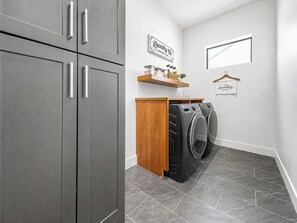 A laundry room with a washing machine, a dryer, and a wooden cabinet. - Valencia - 35' Ceilings - Private Pool - Biltmore (Phoenix)