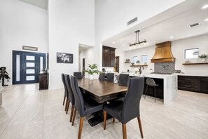 A modern kitchen with dark cabinets, a wooden dining table, and black chairs. - Valencia - 35' Ceilings - Private Pool - Biltmore (Phoenix)
