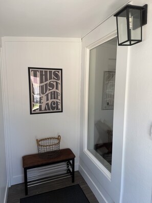 A hallway with a bench, a framed inspirational quote, and a black wall-mounted light fixture.