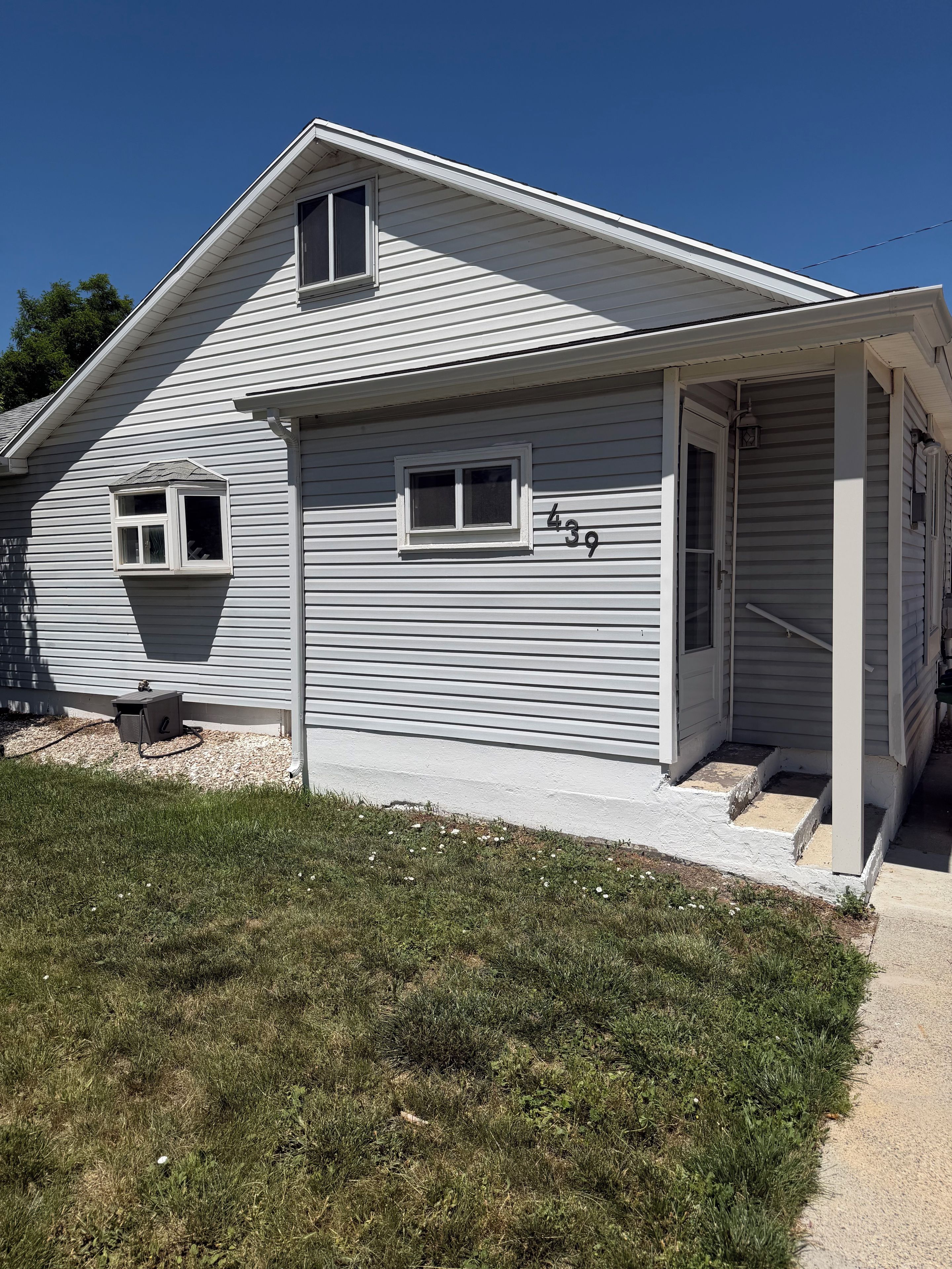 Una casa a un piano con garage, un piccolo portico e il numero 439 sul lato.