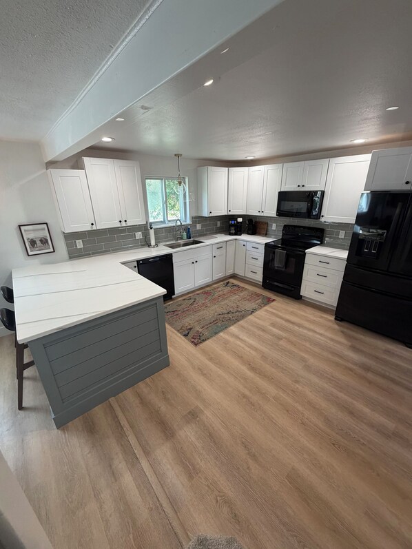 A modern kitchen with white cabinets, a black refrigerator, and a microwave. - 5 Minute Walk to Kendrick Park and Main Street - Peace in the Middle of Town! (Sheridan)