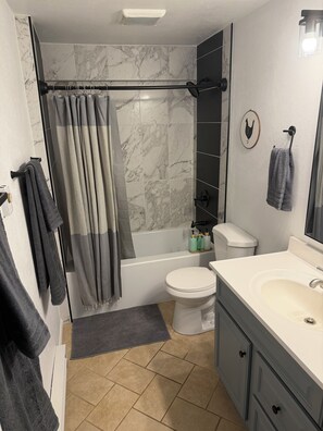 Een badkamer met een bad, toilet en wastafel.