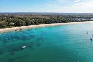 Eine Küstenlandschaft mit Strand, klarem türkisblauem Wasser und einem Boot.