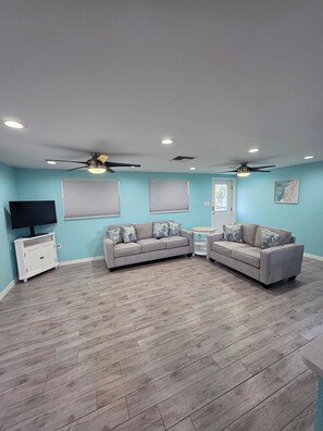 A living room with two grey sofas, a white TV stand, and a ceiling fan. - Hooked on Hudson (Hudson)