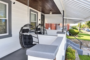 A covered porch with two black wicker chairs and a grey bench. - Cincy 5BR Retreat | Xavier + Zoo | Sleeps 7 (Cincinnati)