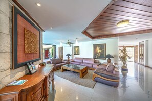 En rummelig lobby med reception, lædersofaer, et sofabord og en Buddha-statue.