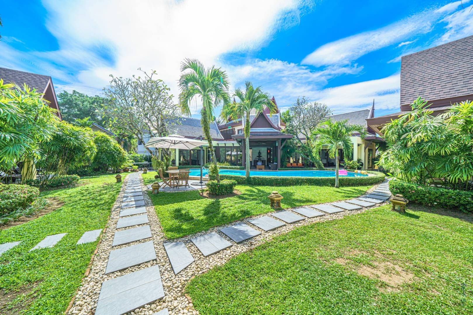 Een resort met een zwembad, een overdekt buitenzitgedeelte en een pad van natuursteen.