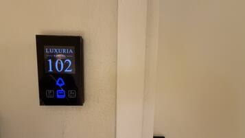 A digital display on a wall indicating room number 102 with options for Do Not Disturb, Occupied, and Make Up Room.