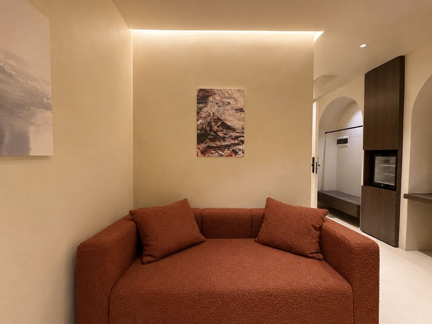 A modern interior with a sofa, a painting, and a built-in refrigerator.