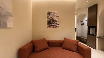 A modern interior with a sofa, a painting, and a built-in refrigerator.