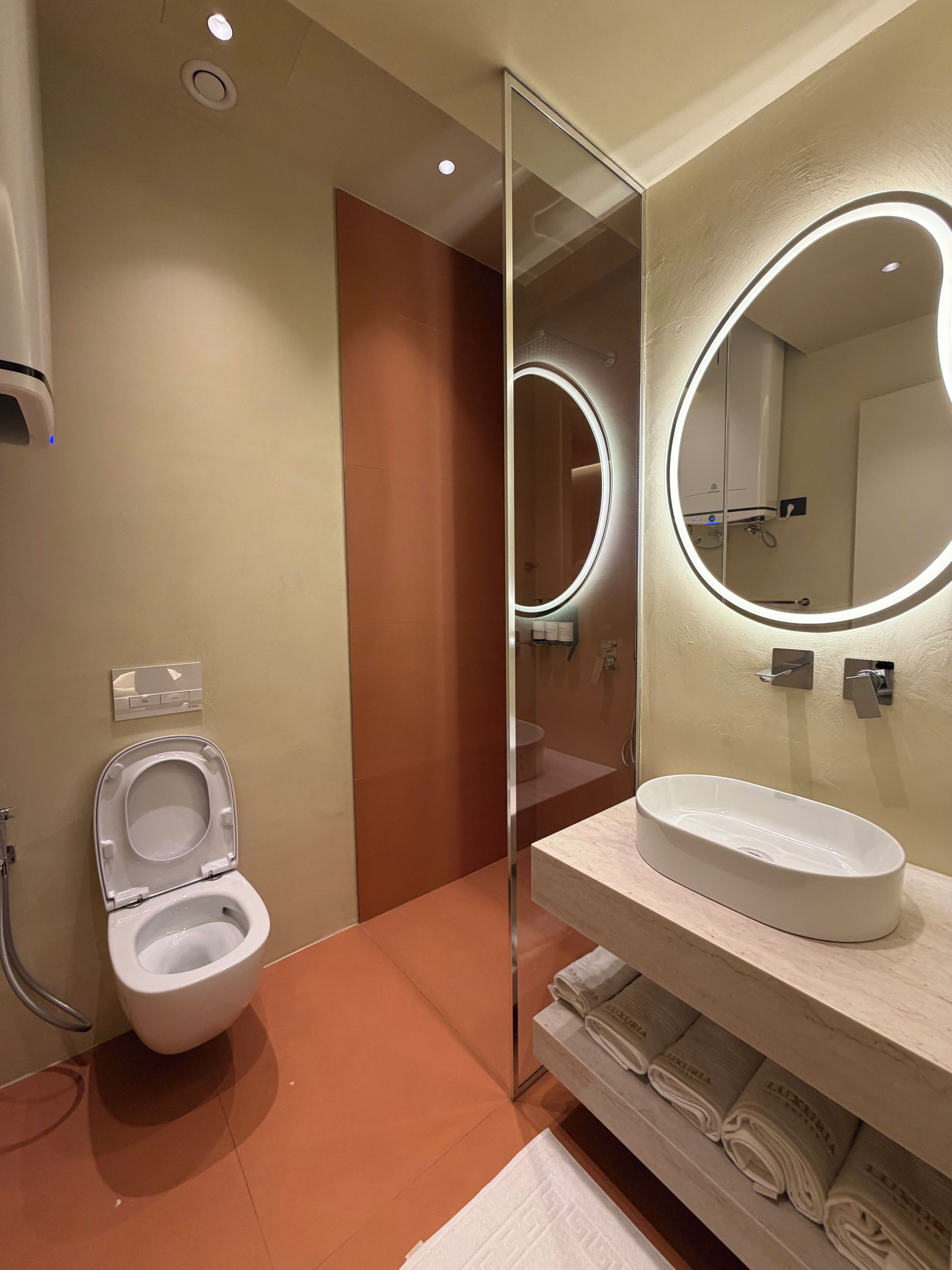 Un baño moderno con inodoro, lavamanos con espejo y un perchero para toallas.