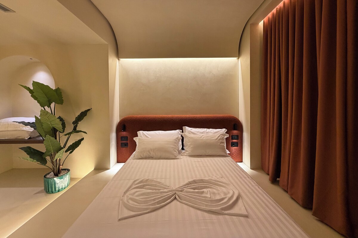 A hotel room with a bed, a potted plant, and a curtain.