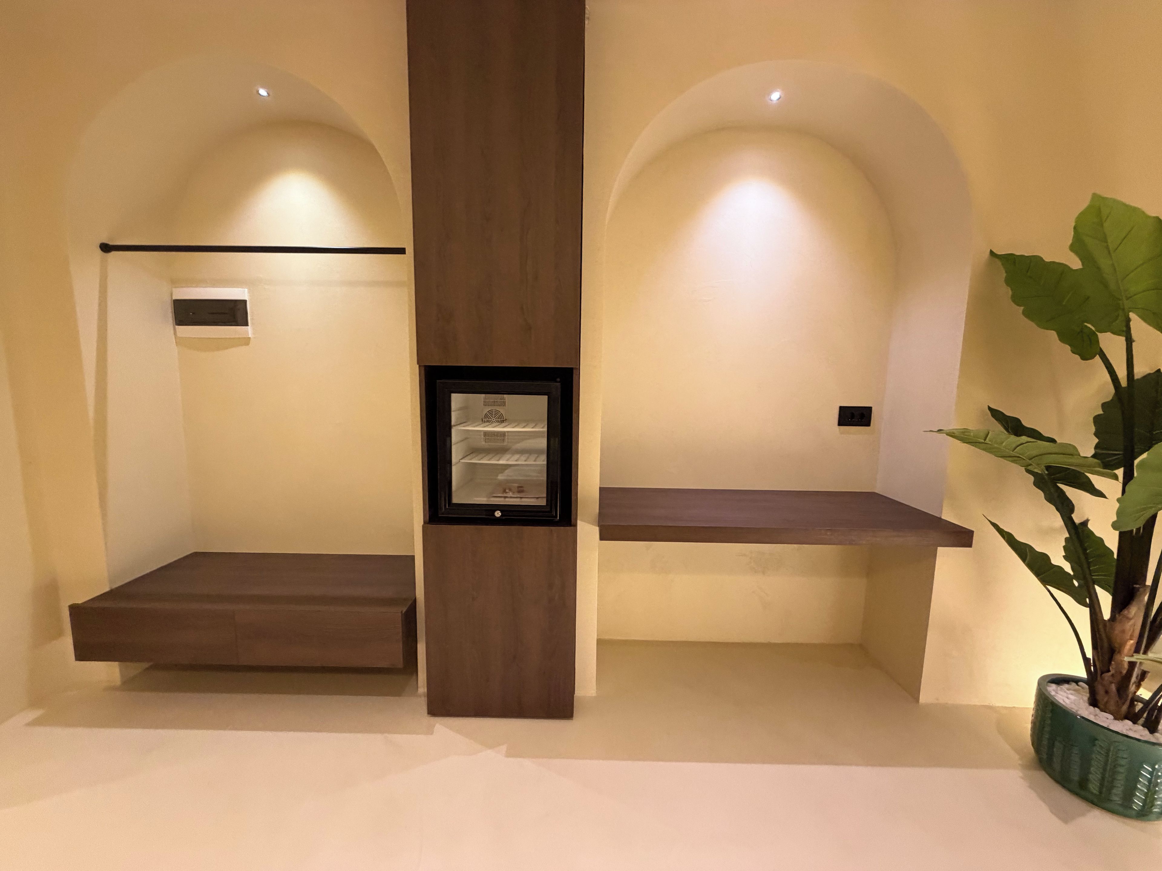 Habitación de hotel con un banco de madera, una planta en maceta y un cuadro en la pared.