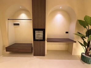 A hotel room with a wooden bench, a potted plant, and a framed picture on the wall. - Luxuria Suites (Tiranë)
