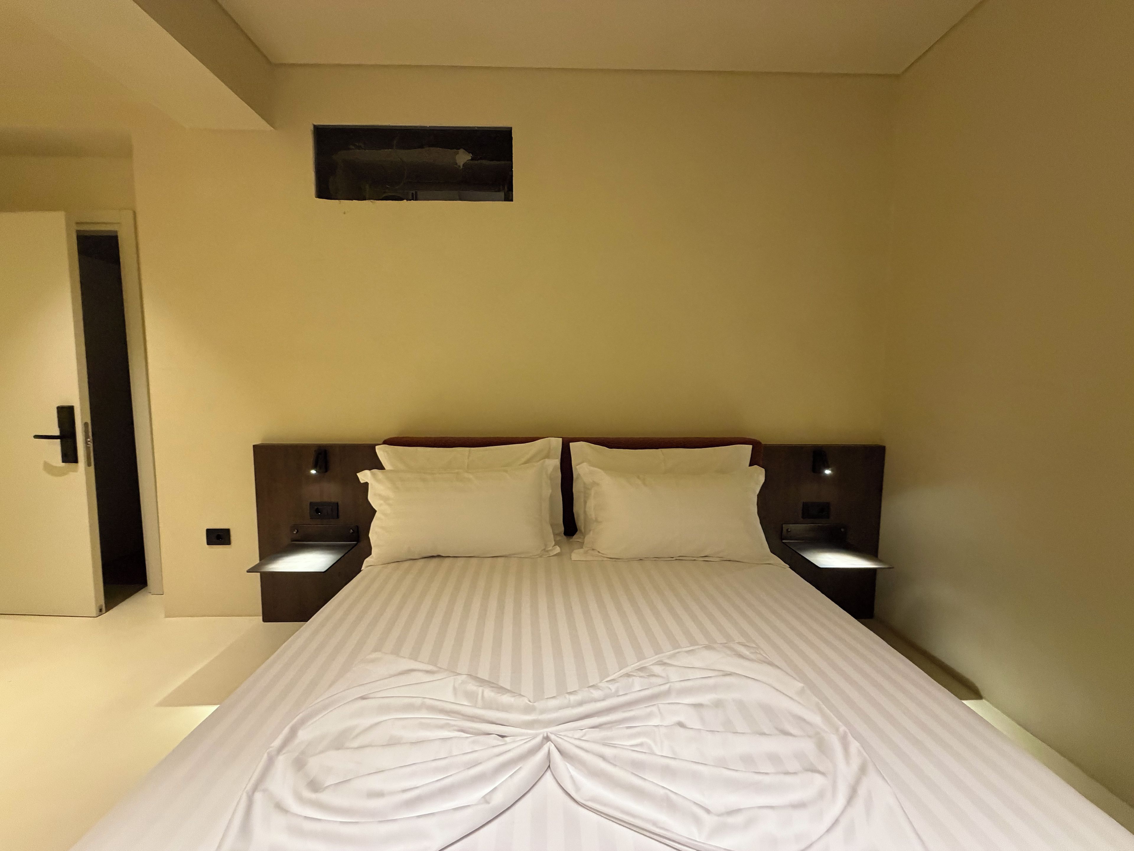 A hotel room with a bed, two bedside tables, and a door.