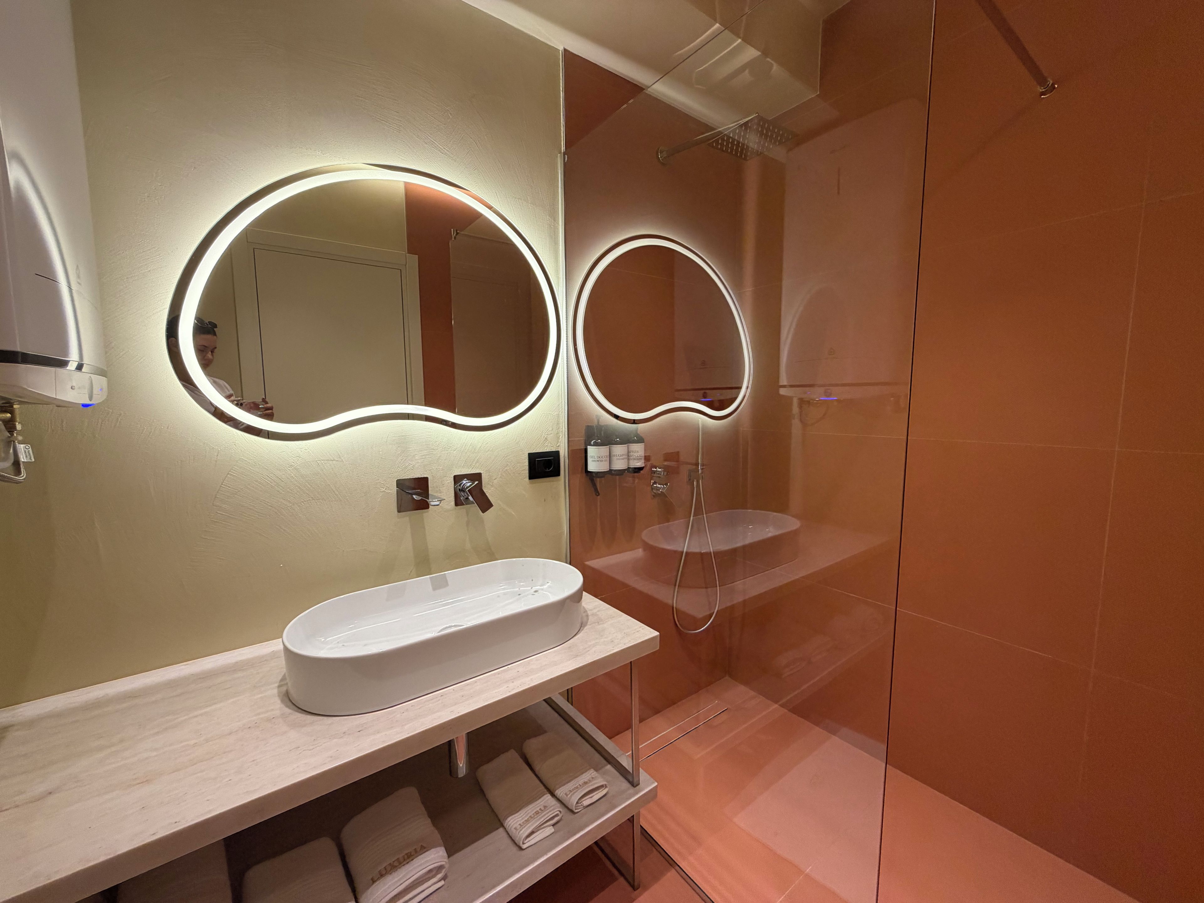 A modern bathroom with a large mirror, a sink, and a shower.