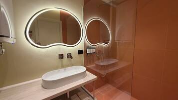 A modern bathroom with a large mirror, a sink, and a shower.