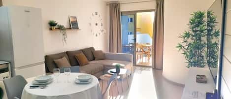 A modern living room with a dining area, a sofa, a coffee table, and a clock on the wall.