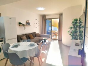 A modern living room with a dining area, a sofa, a coffee table, and a clock on the wall. - Ares Holiday Home in the heart of the island (Costa Antigua)