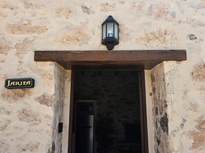 A rustic stone building entrance with a wooden door frame, a sign reading 'JARIFA', and a lantern above. - La Montañeta - Tefia Suites (Tefía)