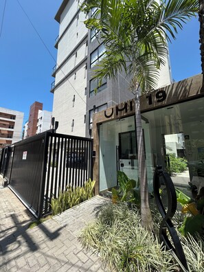 Un bâtiment moderne avec une entrée en verre, une enseigne portant le chiffre « 19 » et une clôture en métal noir.