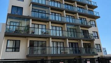 Um edifício com várias andares, varandas, janelas amplas e portão fechado.