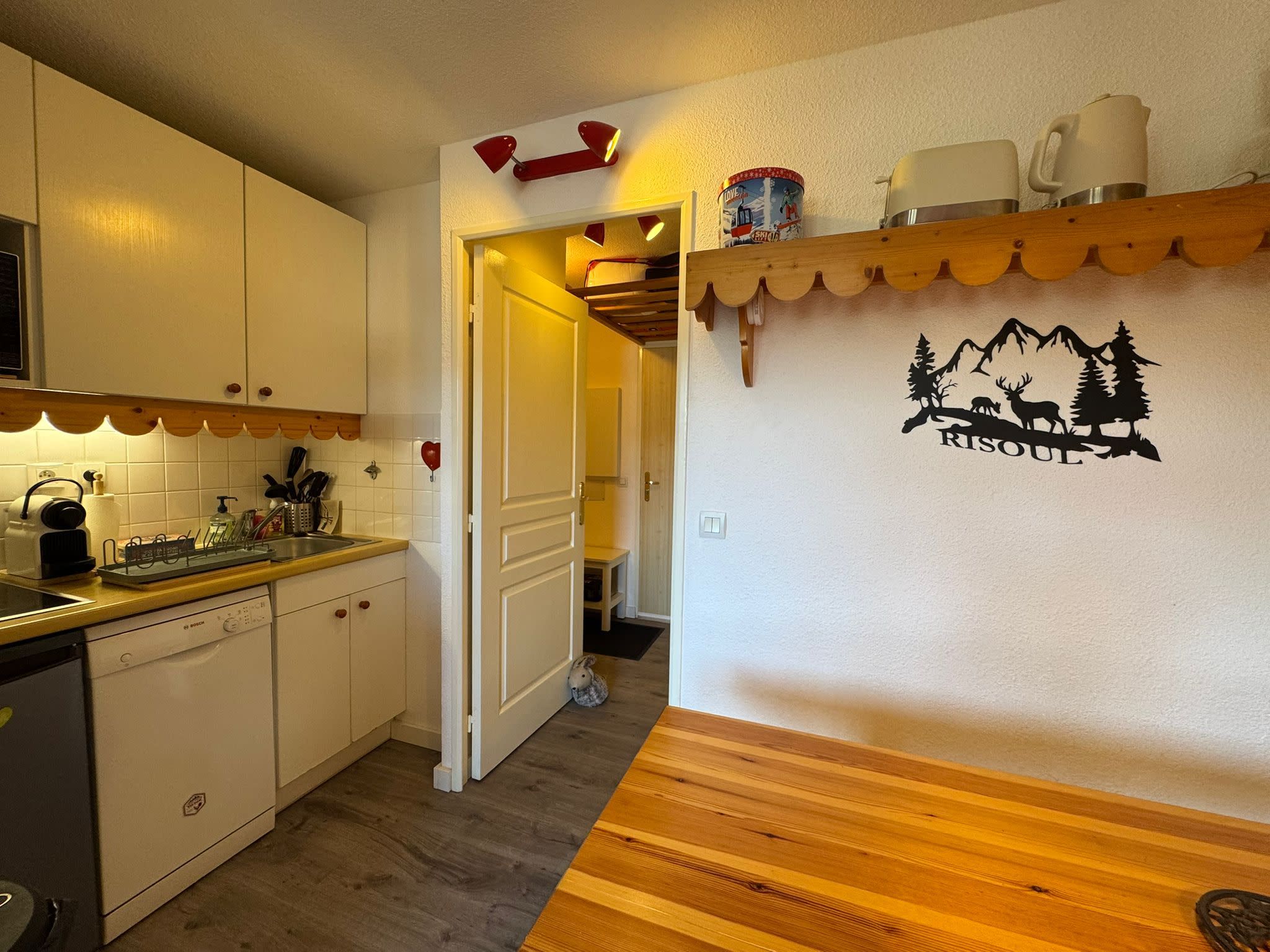 A kitchen with white cabinets, a Bosch dishwasher, and a wooden countertop.