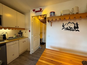Una cocina con armarios blancos, lavavajillas Bosch y encimera de madera.