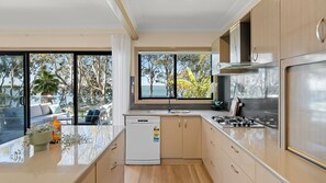 A modern kitchen with a built-in dishwasher, a stove, and a large window offering a view of the outdoors.