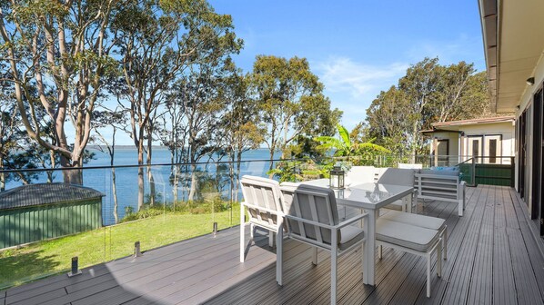 A deck with outdoor furniture overlooking a body of water and trees.