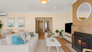 A living room with a sofa, coffee table, fireplace, TV, and artwork on the walls.